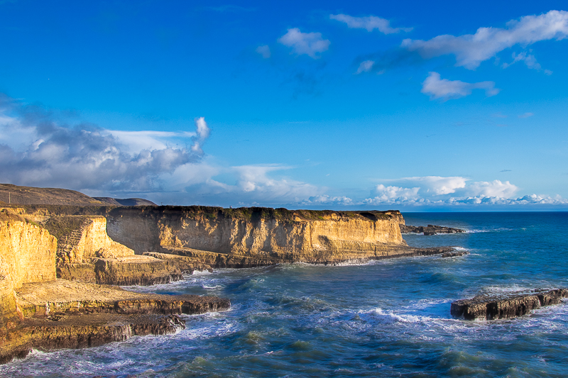Santa Cruz coast — golden sedimentary cliffs drop to tide pools and crashing surf